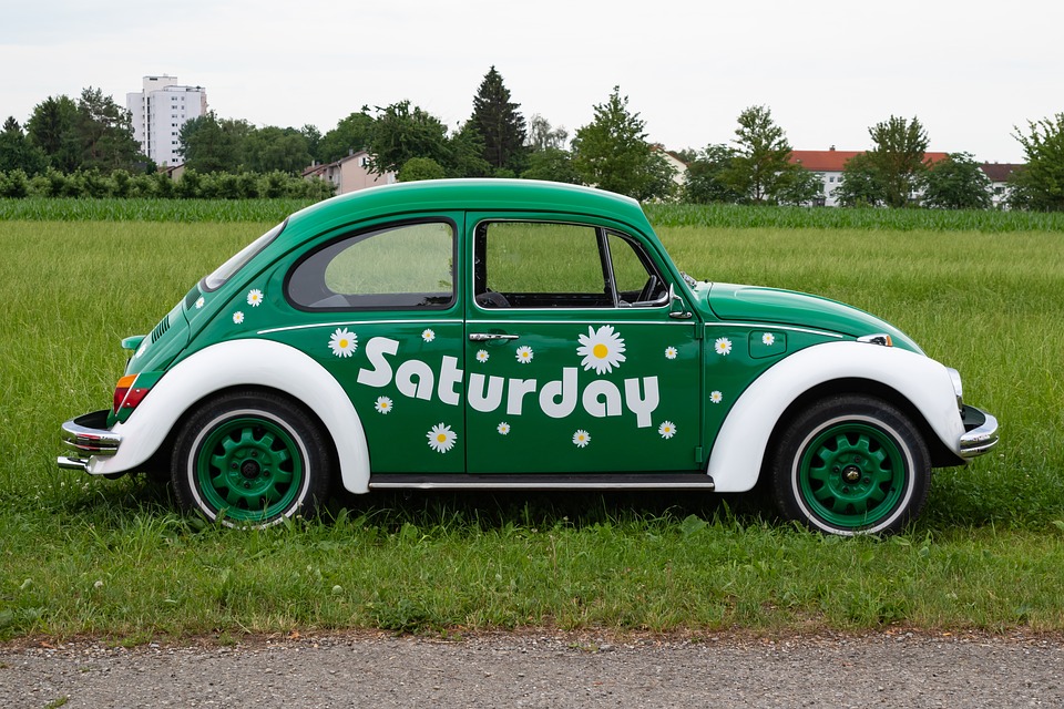 A green Volkswagen Beetle car with the word "Saturday" written on the side of it.