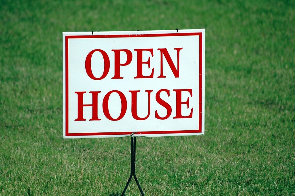 A white sign with red writing that reads, "Open House."